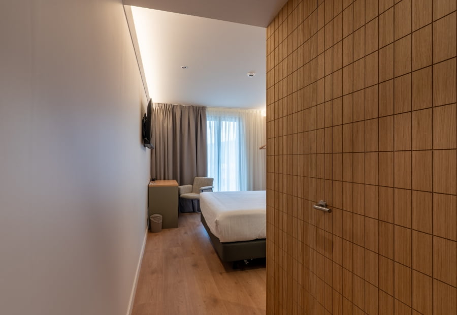 Habitación doble vista del pasillo de la habitación Habitación doble con escritorio, sillón y televisión